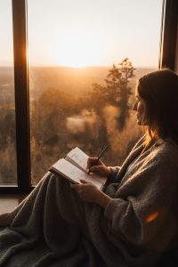 Person journaling peacefully at sunrise with open Life Compass