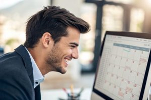 Focused young professional smiling at a task planning screen.