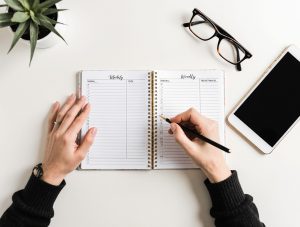 Hands writing weekly goals in an open productivity planner
