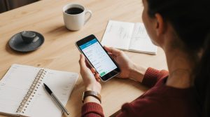 Smartphone with glowing habit tracker app screen next to journal and coffee